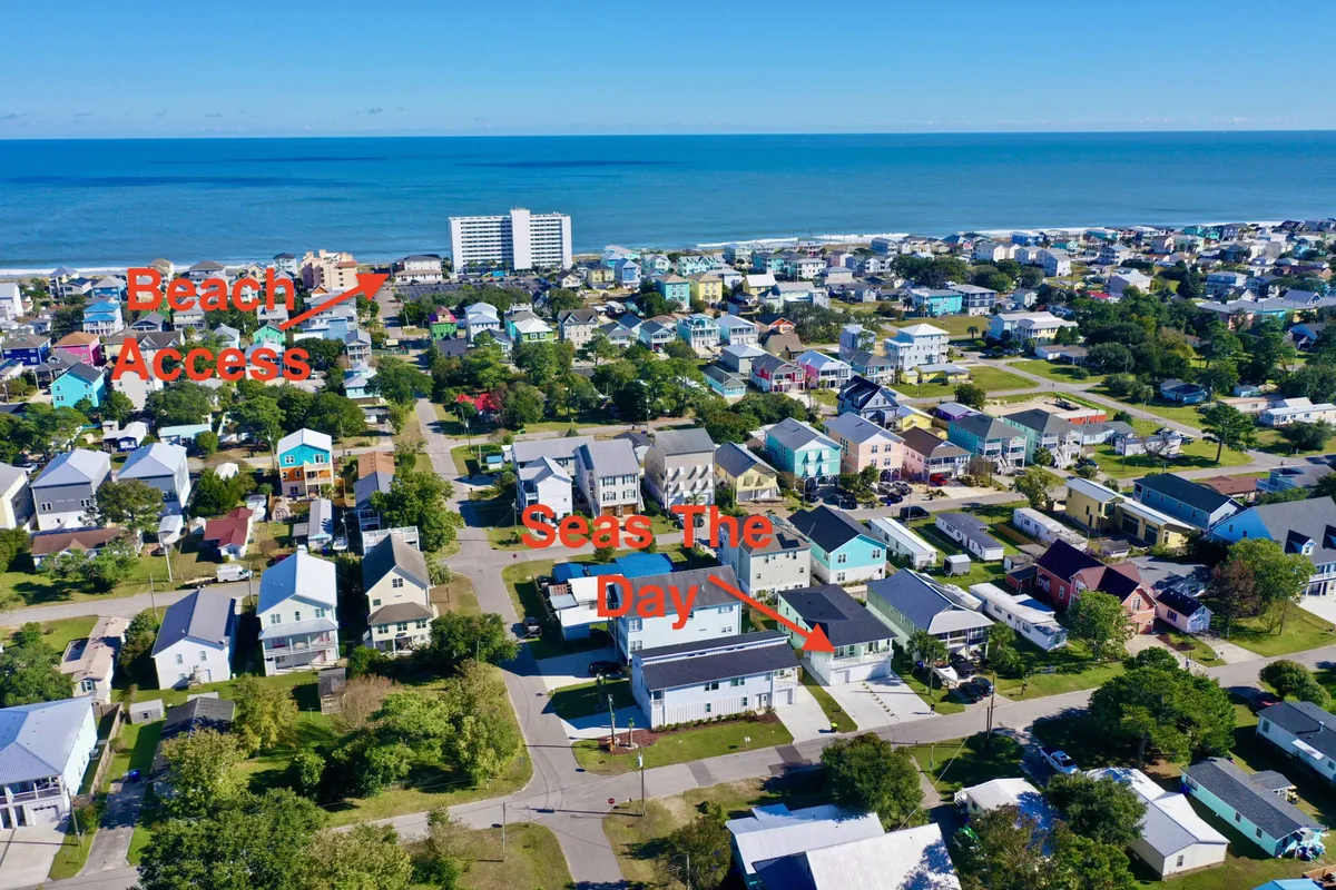 This scene highlights easy access to the beach with a sandy path, coastal homes in view, and a sweeping ocean vista. The image radiates a relaxed beach-town vibe, with the potential for beach outings, community exploration, and scenic walks.