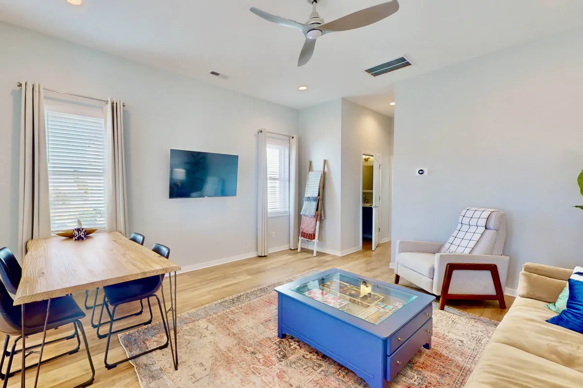 A dining area featuring a large table with chairs, a comfortable sofa, a coffee table, and a television in view. The arrangement suggests a space for both shared meals and casual entertainment, with an inviting, comfortable atmosphere.